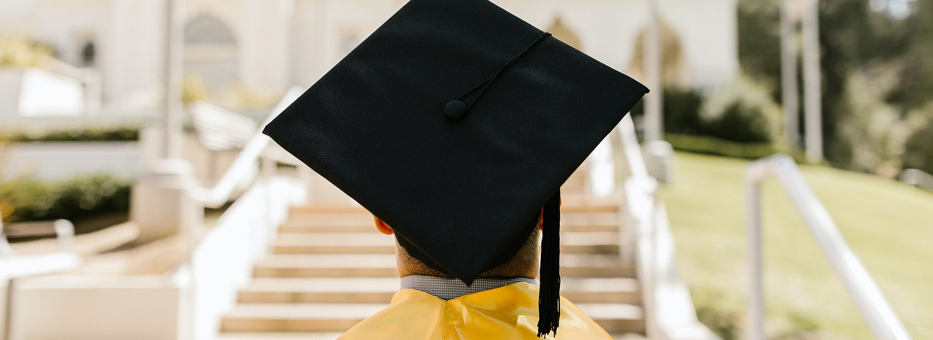 Pessoa de costas com beca e chapéu de formatura 