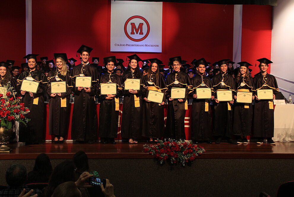 Alunos com becas seguram diplomas de formatura