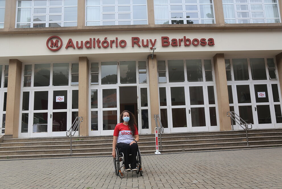 mulher sentada em uma cadeira de rodas em frente ao auditório do Mackenzie 