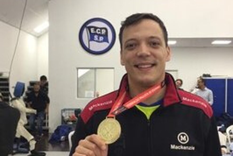 Nicolas Silva sorrindo e segurando uma medalha de ouro