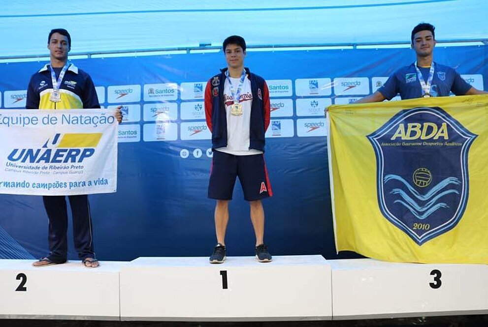 Três homens sorrindo para a foto com medalhas nas mãos