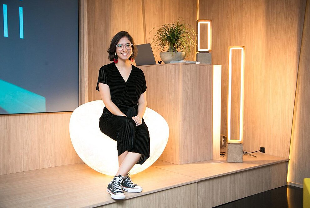 Uma jovem mulher ao lado de uma luminária em formato retangular
